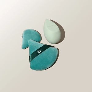 Teal makeup sponges with black bands and one white teardrop sponge, angled