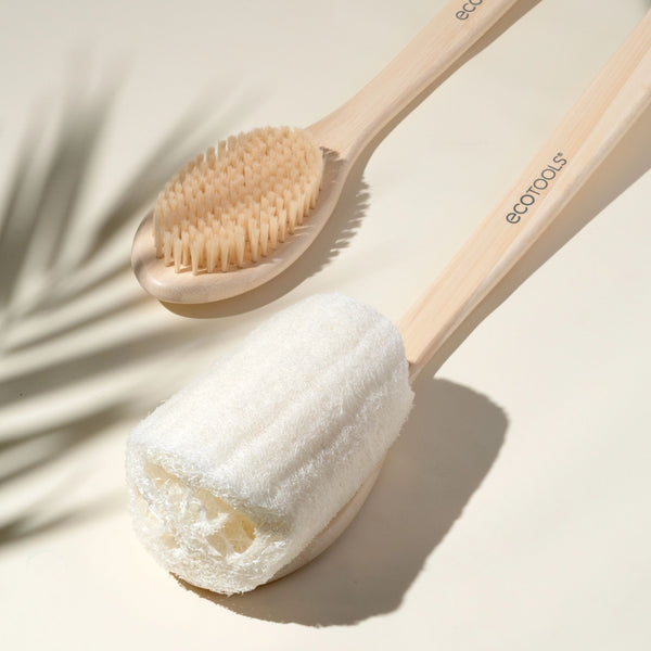 Loofah brush with textured circular scrub head on a light wood handle