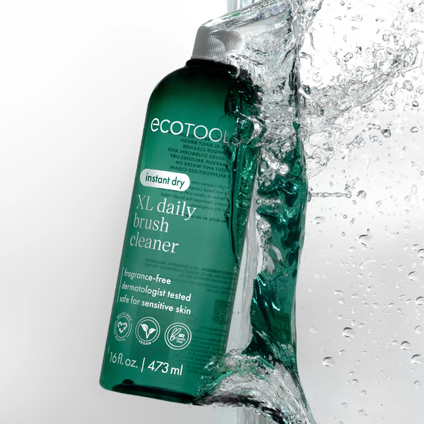 Green XL daily brush cleaner bottle with splashing water droplets beside it.