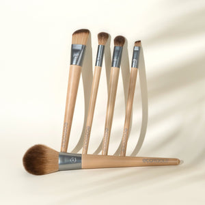 Five makeup brushes with beige handles, silver ferrules, and brown bristles