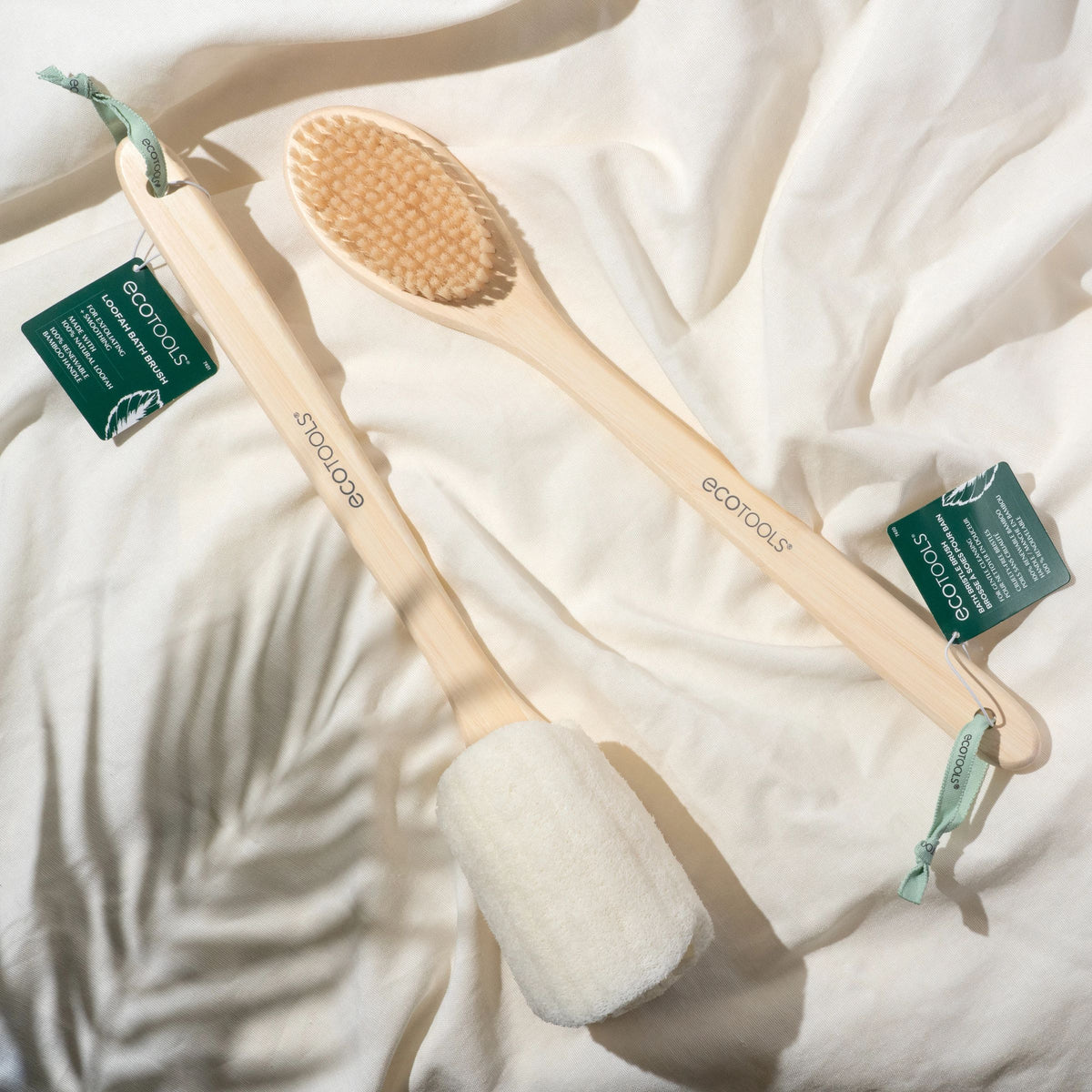 Wooden bath brush with soft bristles and green tags on a white cloth background