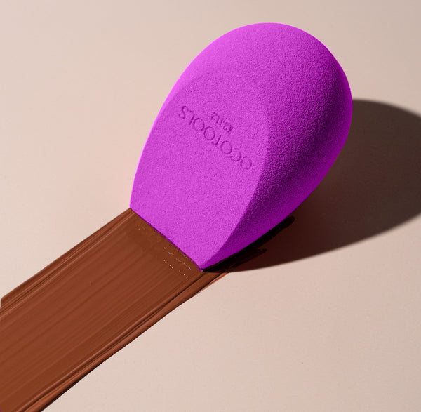 Purple makeup sponge applicator tip on a wooden handle for makeup blending