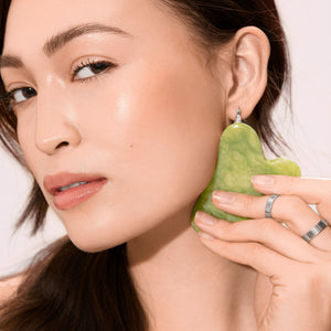 Heart-shaped jade face tool held on cheek during skincare