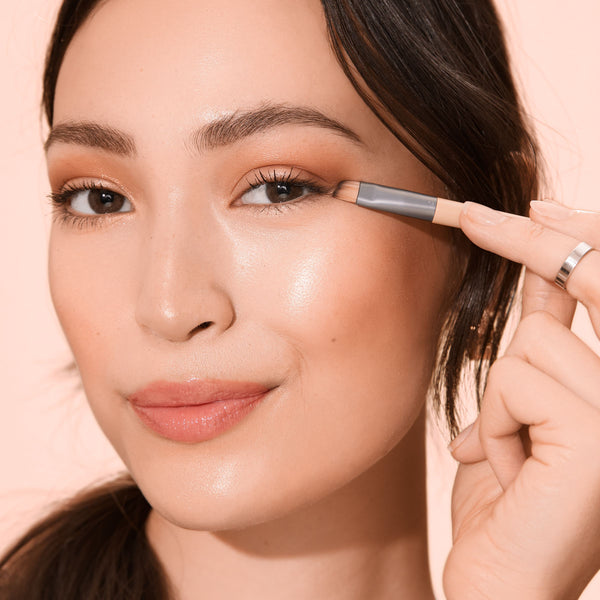 Eye makeup brush held near the eyelid with fine angled bristles for shadow application
