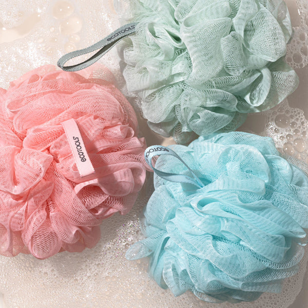 Assorted mesh cleansing poufs in pink, mint, and light blue with fabric tags