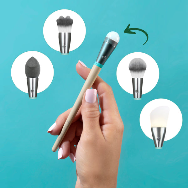 Hand holding an interchangeable makeup brush with beige handle and gray bristles