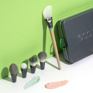 Interchangeable makeup brushes with gray heads and teal collars beside three cosmetic swatches
