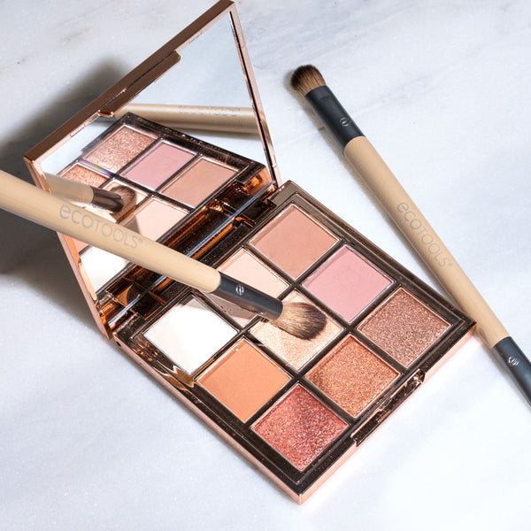 Eye makeup brush set with two beige handles and angled dark bristles next to an eyeshadow palette