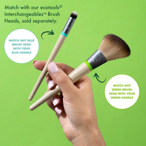 Two interchangeable makeup brush handles with green and teal end caps held in hand