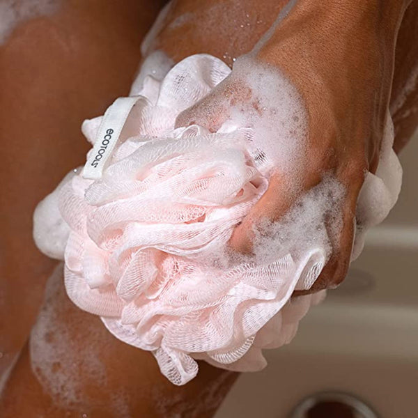 Delicate bath sponge in hand, with soft pink and white loofah-like fibers