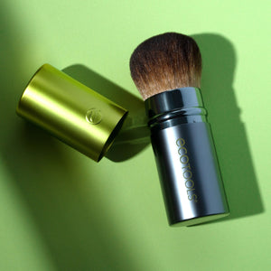 Retractable face makeup brush with soft brown bristles and green metal tube