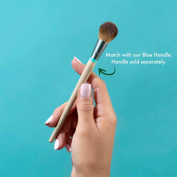 Rounded cheek brush with brown bristles and light handle held in a hand